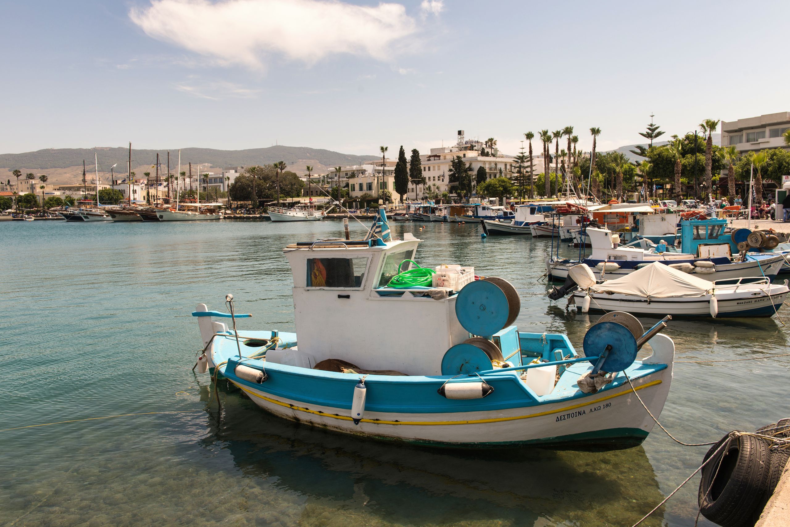 Παραδοσιακό ψαρόβαρκο δεμένο σε ηλιόλουστο λιμάνι με βουνά στο βάθος